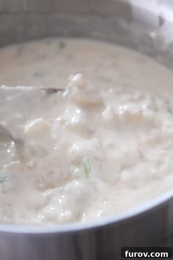 Stirring loaded baked potato soup in pot.