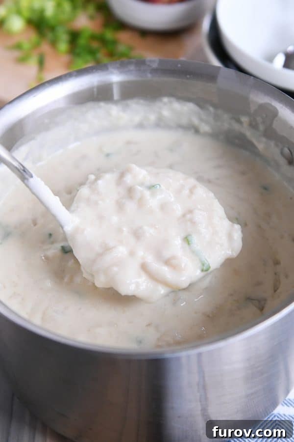 Scooping out ladle of easy loaded baked potato soup in pot.
