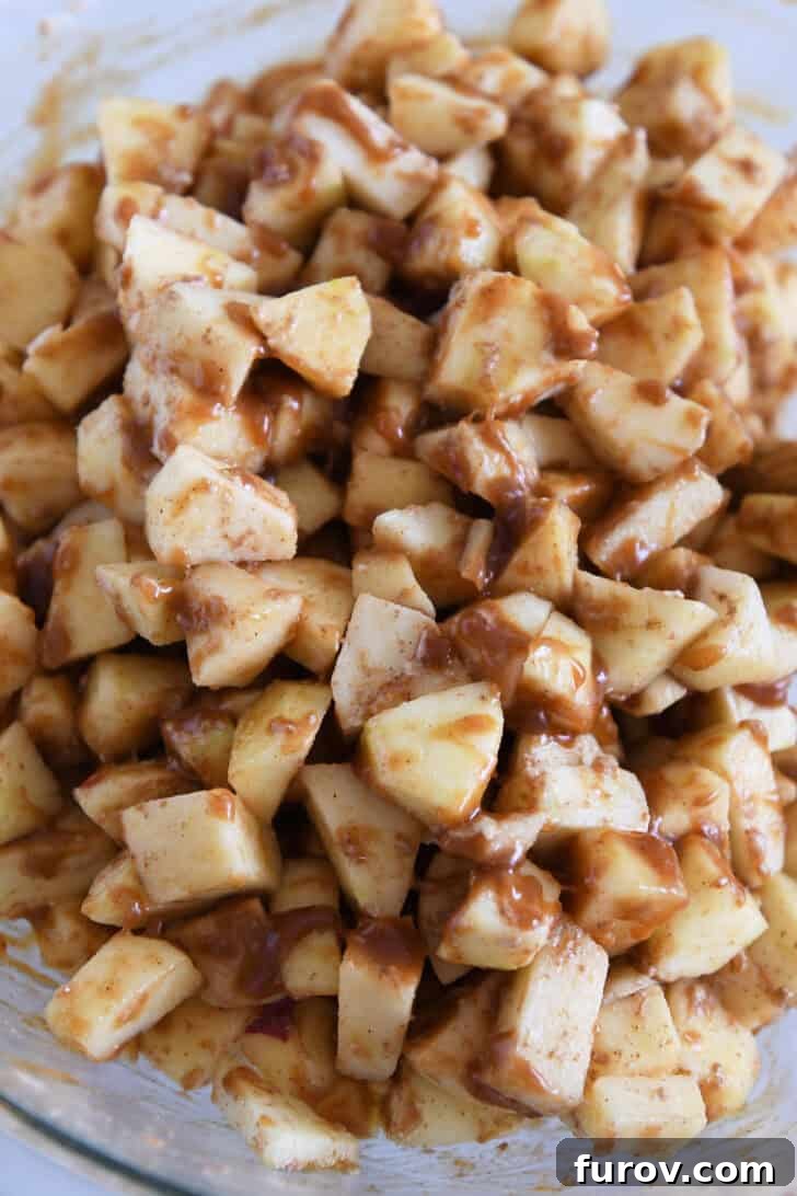 Gooey Caramel Apple Crumble 3 A glass bowl filled with freshly chopped apples mixed with a generous pour of rich caramel sauce, ready for the crisp topping.