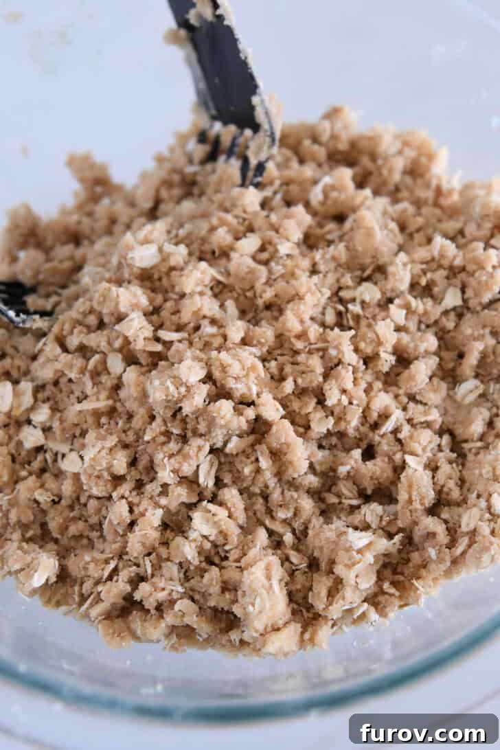 Gooey Caramel Apple Crumble 4 A glass bowl showcasing the crumbly mixture for the crisp topping, featuring flour, brown sugar, oats, and cold butter pieces.