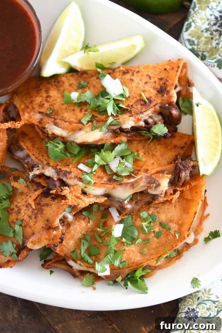 Ultimate Slow Cooker Birria Tacos 2 Three corn tortillas filled with beef and melty cheese topped with cilantro and onions on white platter.