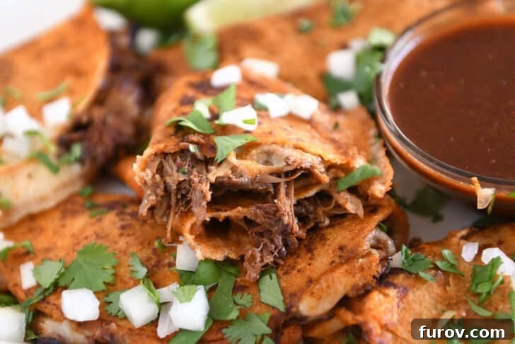 Ultimate Slow Cooker Birria Tacos 13 Birria taco with beef and melted cheese split in half on white tray cilantro and white onions.