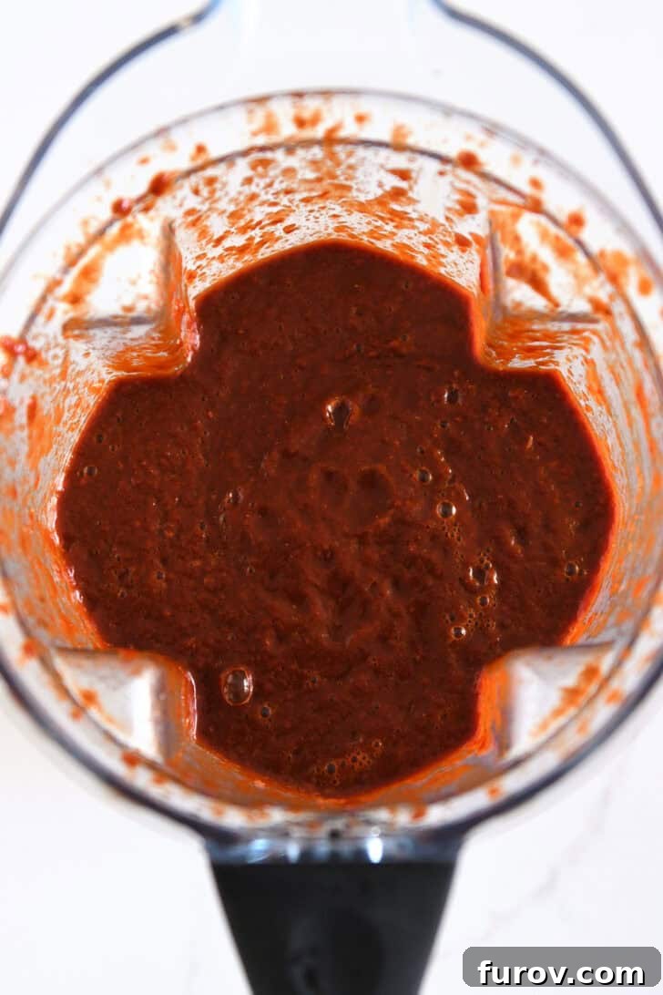 Ultimate Slow Cooker Birria Tacos 5 Top down view of blender with blended mixture of Mexican chiles, onion, and broth.