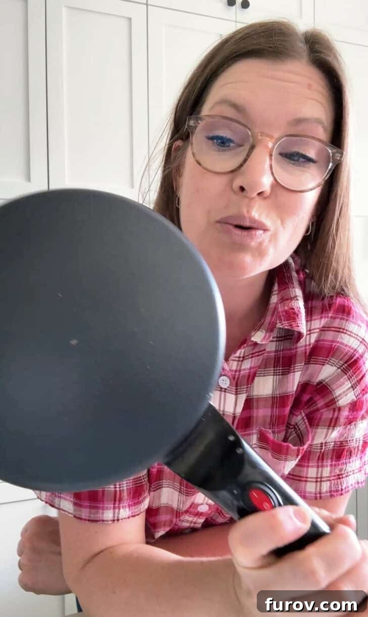 Woman holding electric crepe maker.