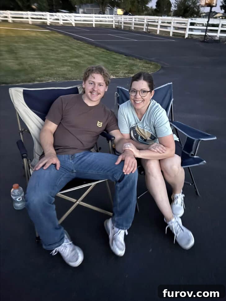 Mom sitting by adult son in camping chairs.