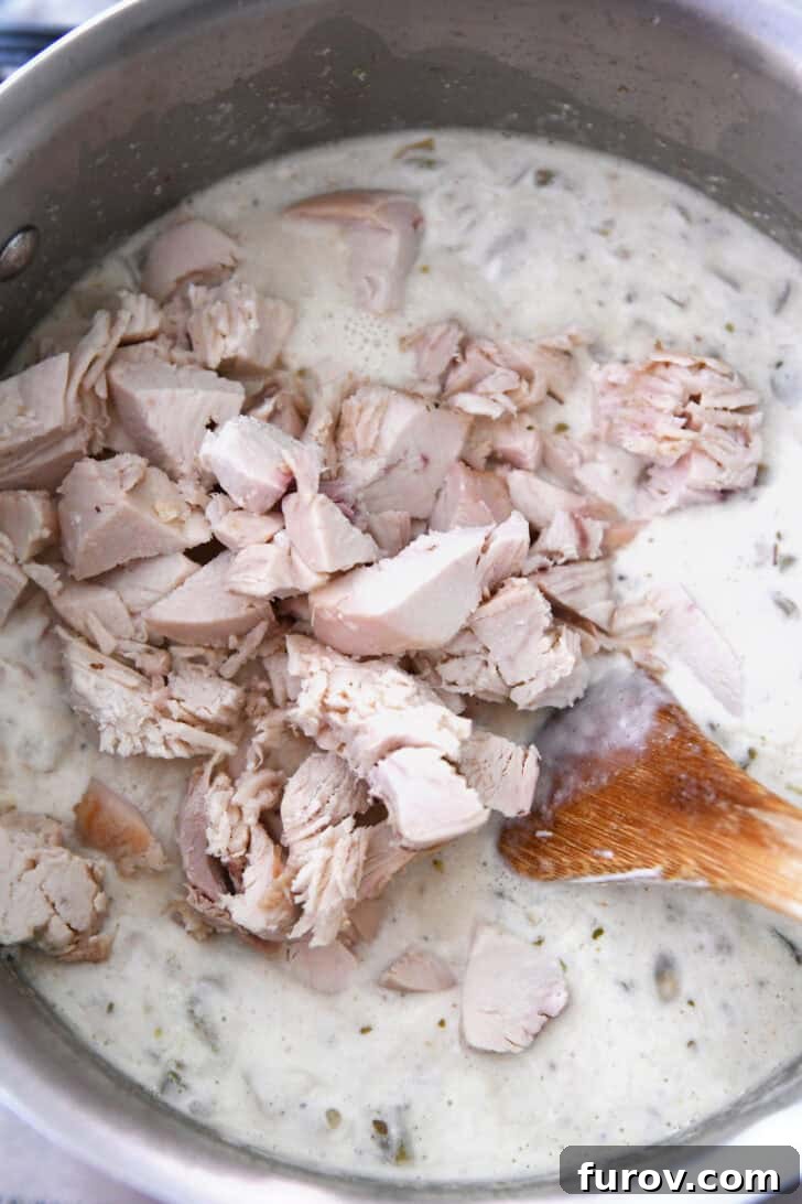 Velvety White Chicken Chili 4 Top down view of an instant pot full of creamy white chicken chili with chopped chicken, ready to be stirred and served.