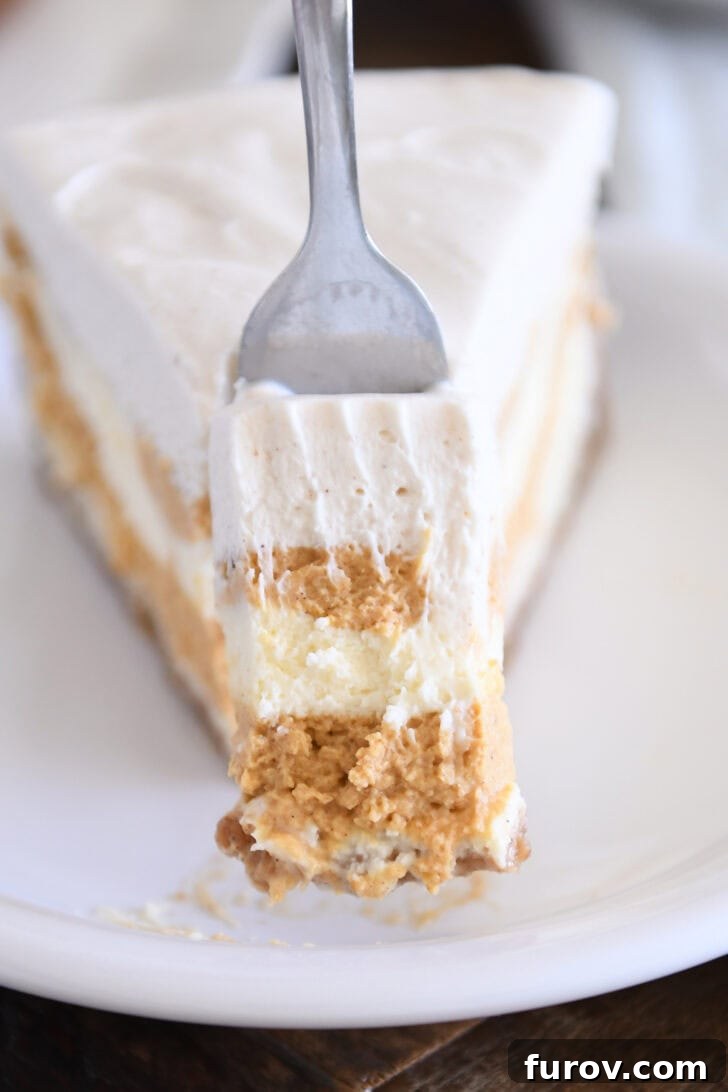 Golden Pumpkin Swirl Cheesecake 13 A close-up of a slice of pumpkin swirl cheesecake on a white plate, with a small bite removed, highlighting the creamy texture and the intricate swirl pattern within the layers, topped with white chocolate mousse.