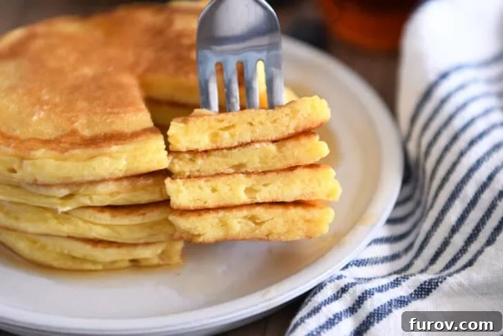 Four triangle slices cut out of a stack of four cottage cheese pancakes on a gray plate, ready to be served.
