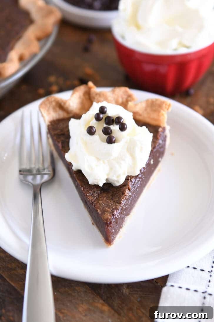 Velvet Chocolate Perfection 2 A perfectly sliced triangle of chocolate chess pie, garnished with a dollop of fluffy whipped cream and sparkling chocolate crisp pearls, rests elegantly on a white plate with a fork poised nearby.