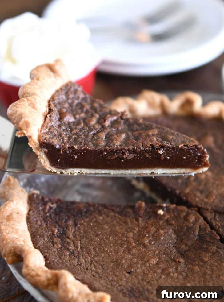 Velvet Chocolate Perfection 7 A perfectly portioned slice of chocolate chess pie being lifted gently with a silver pie server, showcasing its rich, dark filling and crackly top.