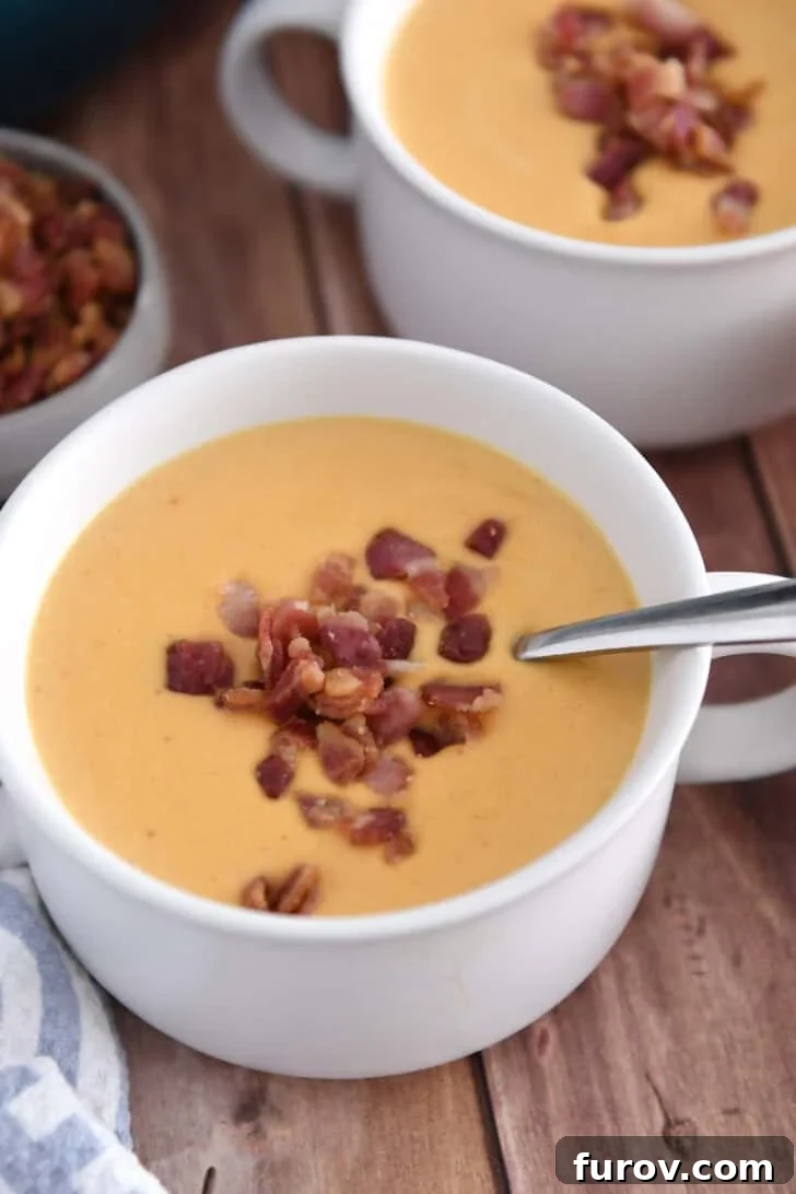 Two white bowls of roasted butternut squash soup, elegantly topped with cooked and crumbled bacon bits.