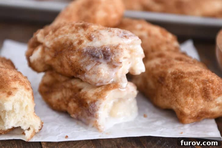 Two half cinnamon twists dipped in icing and stacked on each other, showcasing their fluffy texture and sweet coating.