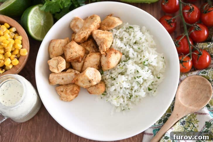 A white bowl with a base of fluffy cilantro lime rice topped with perfectly cooked and seasoned chicken pieces.
