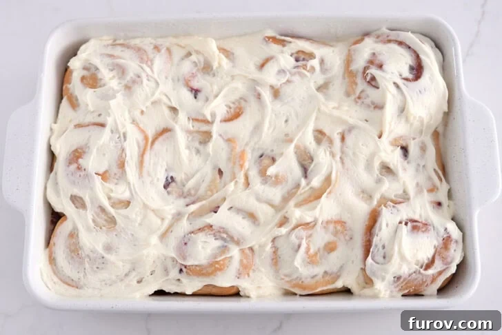 Baked sweet rolls in white 9X13-inch pan spread with sweet cream cheese icing.