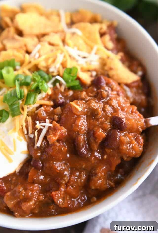 A hearty serving of red chili, brimming with ground beef and beans, presented in a cozy gray bowl, invitingly ready to be savored.