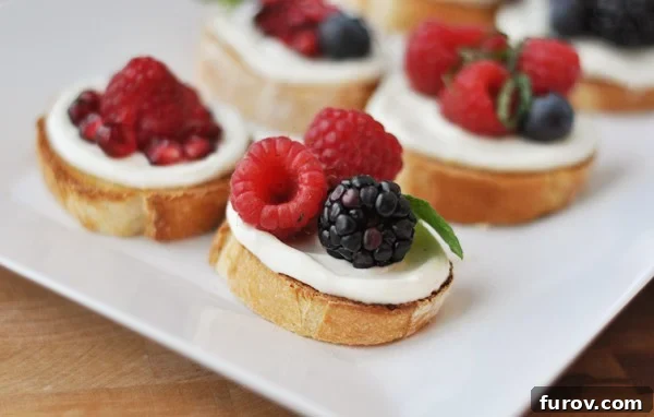 Close-up of a white tray showcasing sweet berry bruschetta with pomegranate, raspberries, blackberries, and blueberries, ready to be served.