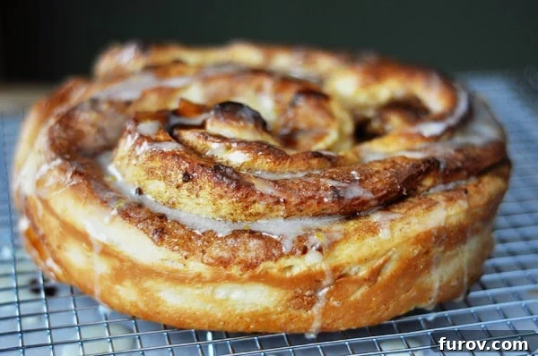 Mastering Giant Cinnamon Rolls A Step by Step Photo Guide 2 A gloriously frosted giant cinnamon roll, resting on a cooling rack, glistening with sweet glaze.