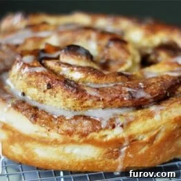 Mastering Giant Cinnamon Rolls A Step by Step Photo Guide 4 A beautifully frosted giant cinnamon roll, captured from an overhead view, glistening with sweet glaze.