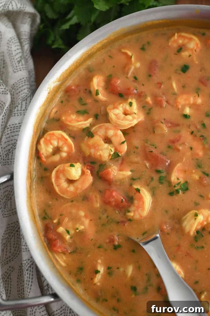 Top down view of a metal pot full of a vibrant shrimp curry, simmering to perfection, ready to be served.