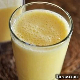 A close-up of a classic Orange Julius in a glass with an orange wedge garnish, showcasing its frothy texture.