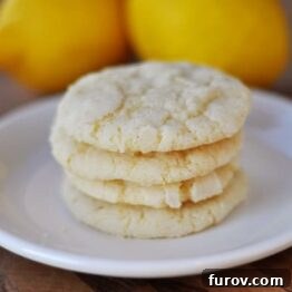 Four lemon cookies stacked on a white plate