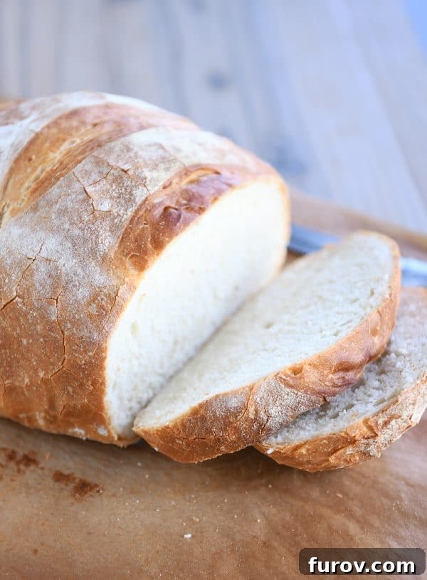 A fresh loaf of rustic crusty bread with two slices expertly cut, revealing its soft interior.
