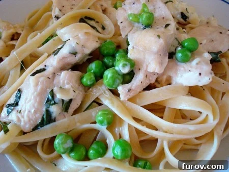 Fettuccine noodles topped with creamy chicken, vibrant green peas, and fresh basil.