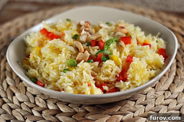 A white bowl showcasing fluffy jasmine rice infused with orange, studded with colorful chopped bell peppers, crunchy cashews, and fresh chives. It's a vibrant and inviting side dish.