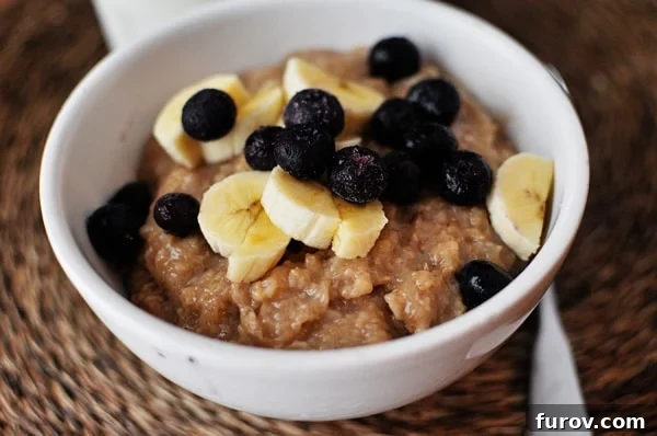 Sweet Maple Brown Sugar Overnight Oats 3 Top view of a white bowl full of cooked oatmeal topped with sliced bananas and blueberries, ready to be enjoyed.