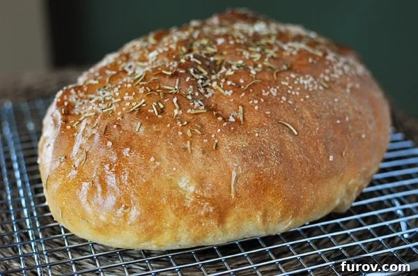 Macaroni Grill's Signature Rosemary Bread 2 golden brown loaf of bread sprinkled with rosemary and salt on a cooling rack