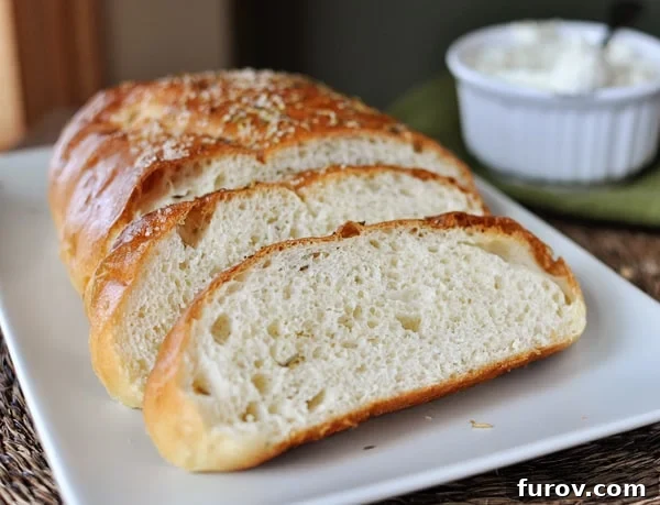 Macaroni Grill's Signature Rosemary Bread 3 Half a loaf of rosemary bread with two big slices in front of the loaf, on a white rectangular plate.