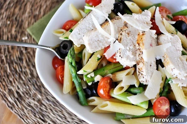 Garden Fresh Penne in Silken Butter Sauce 2 White bowl with cooked penne pasta, asparagus, tomatoes, olives, and chicken strips.