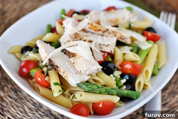 Garden Fresh Penne in Silken Butter Sauce 3 White bowl with cooked penne pasta, pieces of asparagus, cherry tomatoes, olives, and chicken slices.