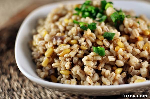 Wholesome Barley Pilaf 3 White bowl with cooked barley and pine nuts, topped with vibrant green onions for a fresh finish.