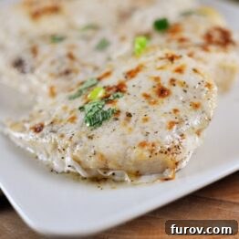 Broiled Parmesan and Lemon Chicken with fresh herbs and lemon slices, presented beautifully.