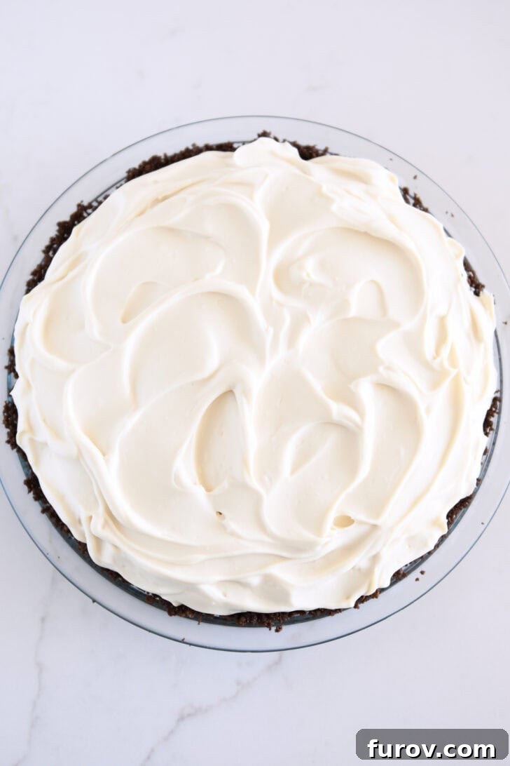 A generous, fluffy cloud of whipped cream mixture dolloped and gently spread across the top of the banana layer, creating a soft, inviting peak.