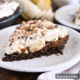 A perfect slice of Banoffee Pie on a white plate, showing all the beautiful layers.