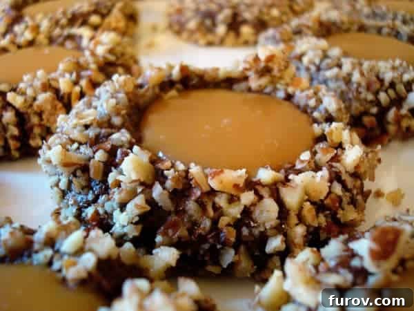 A perfectly baked chocolate thumbprint cookie with a generous dollop of golden caramel in the center, ready to be enjoyed.