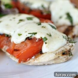 A perfectly plated Grilled Caprese Chicken dish, topped with melted mozzarella and fresh basil.