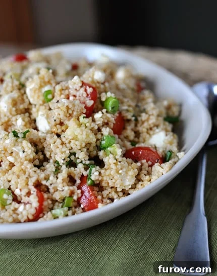 Vibrant Summer Couscous Salad 2 A beautiful white bowl overflowing with a vibrant couscous salad featuring fluffy couscous, bright green peas, and juicy red tomatoes, ready to be served.