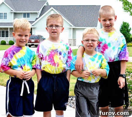 Four little boys proudly wearing their homemade, colorful tie-dye shirts, illustrating a playful, messy summer day.