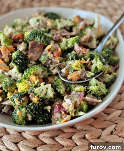 Ultimate Broccoli Salad 3 A close-up shot of a generous serving of homemade broccoli salad in a bowl, highlighting its vibrant green broccoli florets, crispy bacon, and creamy dressing.