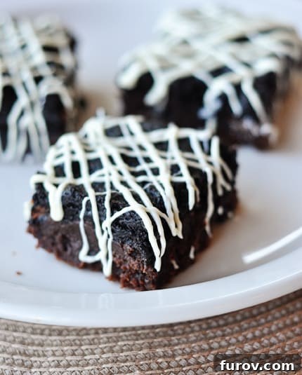 Three Oreo truffle brownies arranged artfully on a white plate, highlighting their visual appeal.