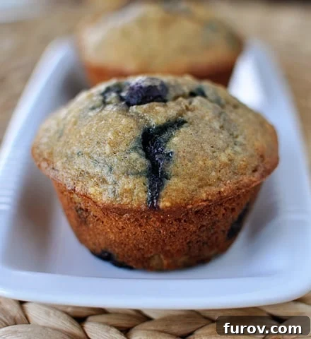 Golden brown banana blueberry muffins lined up neatly on a rectangular white platter, ready to be enjoyed.