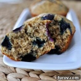 A close-up of a freshly baked banana blueberry muffin, showcasing its golden top and rich texture.