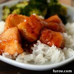 Bourbon Chicken served with white rice and a side of green vegetables.