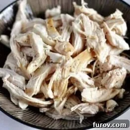 Close-up of freshly cooked, simple shredded chicken in a bowl, seasoned and ready to eat.