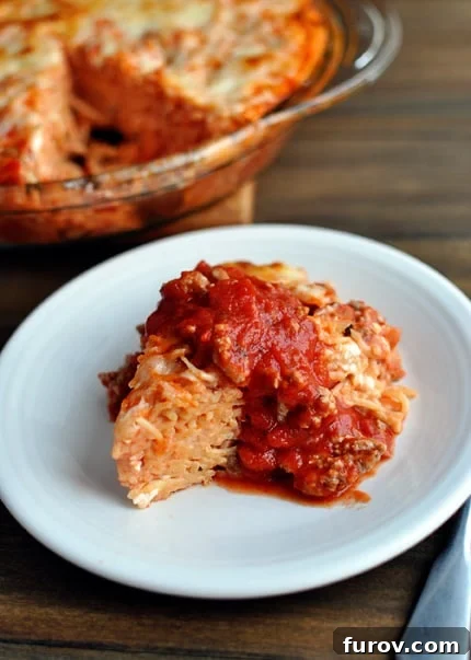 Savory Spaghetti Bake 2 A white plate with a triangle of spaghetti pie covered in rich red spaghetti sauce.