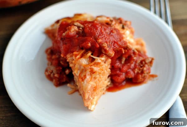 Savory Spaghetti Bake 3 A triangle shaped serving of cooked spaghetti pie topped with red spaghetti sauce.