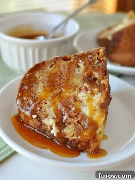 A generous slice of caramel-drizzled apple bundt cake on a pristine white plate, showcasing its moist texture and apple chunks.